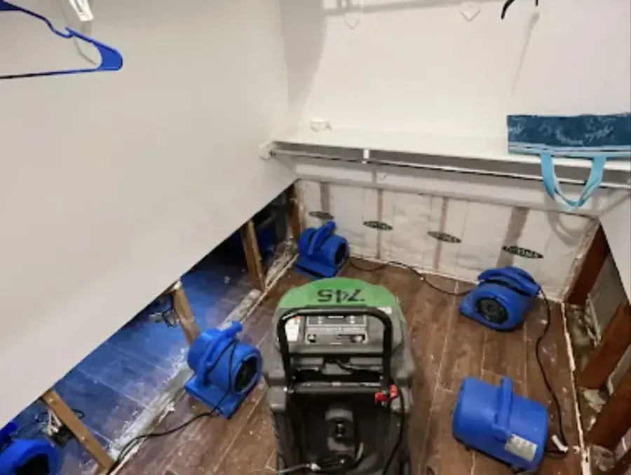 Air movers and a dehumidifier beside flood-cut walls