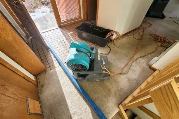 A teal air mover dries the floor beside an open exterior door